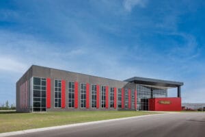 Exterior view during the daytime of the Vaderstad precast building with gray and red accent panels.