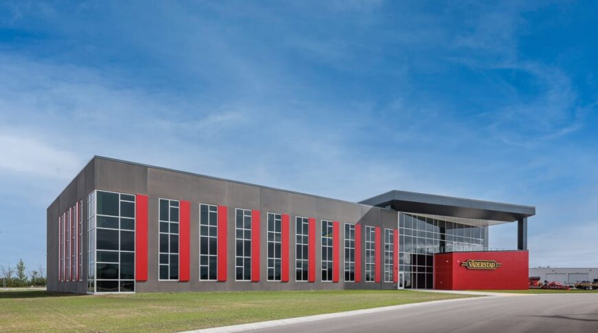 Exterior view during the daytime of the Vaderstad precast building with gray and red accent panels.