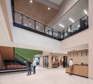 Two-story grand reception area at the Vaderstad North American Headquarters with wood paneling and light green painted accent walls and an open walkway above.