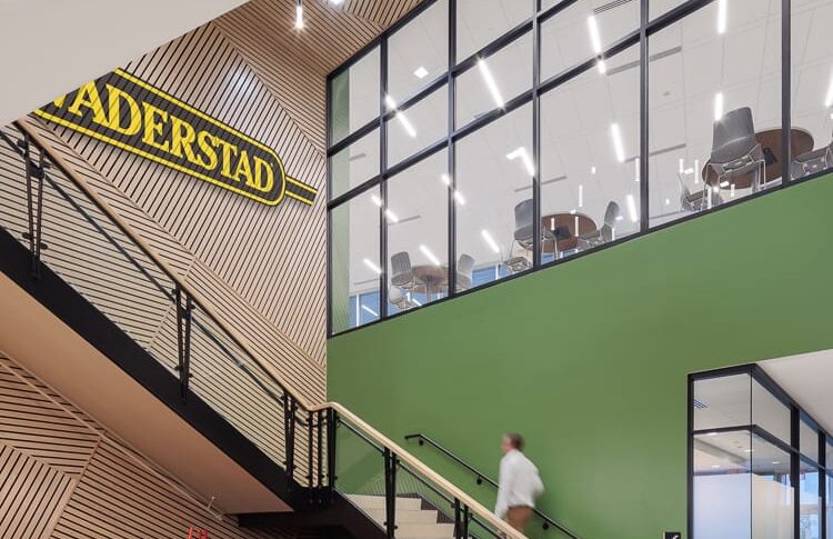 Two-story stairwell with light green and wood paneling accents. A farm implement displayed besides and the sign "Vaderstad" above.