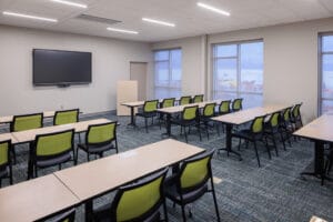 Beige-painted conference rooms with tables to match and light green accented chairs and green and gray carpeting beneath.