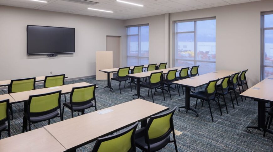 Beige-painted conference rooms with tables to match and light green accented chairs and green and gray carpeting beneath.