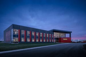 Exterior nighttime image of the gray and red Vaderstad precast building.