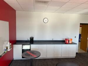 Beige wall with complimentary beige-colored lower cabinetry with a black countertop.