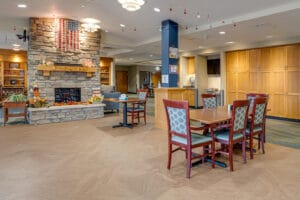 New dining room flooring added in dining room at nursing home with tables and chairs throughout backdropped by fireplace behind.