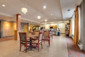 Newly done laminate flooring in nursing home dining rom with tables and chairs throughout and bright big windows overlooking the grounds.