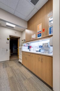 Hallway at clinic with upper and lower cabinetry for medical supplies and sink station.