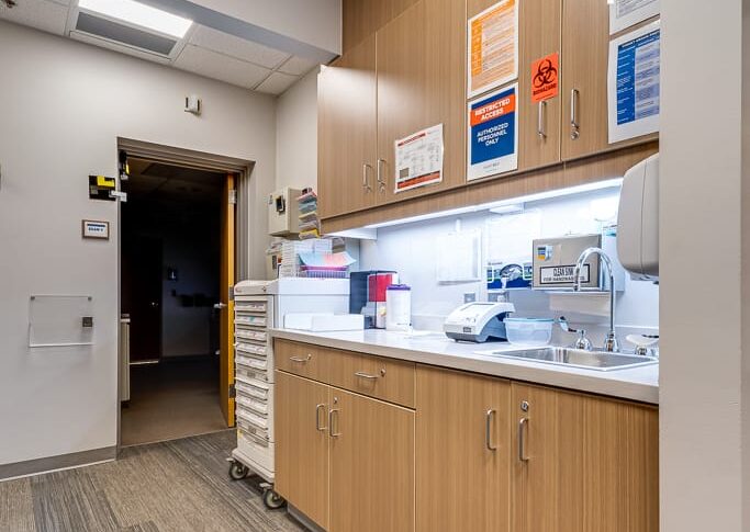 Sanford Hillsboro-Low Res-27 Hallway at clinic with upper and lower cabinetry for medical supplies and sink station.