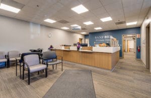 Entrance to Sanford Hillsboro Clinic looking towards reception desk and blue wall behind with the words "Sanford Hillsboro Clinic" in silver.