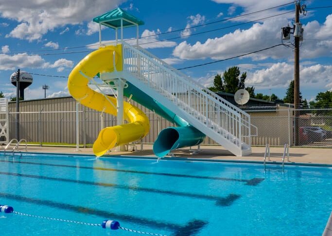 Gwinner Aquatic Center-Low Res-39 Outdoor swimming pool with two waterslides and blue skies behind.