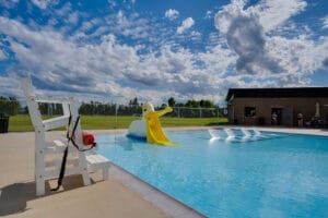 Zero-entry pool with pelican-shaped toddler slide and four sunken concrete lounge chairs.