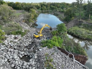 Aerial view of Mayville Dam with bright yellow excavator clearing debris.