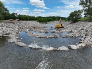 Goose River rock riffles being placed by big yellow excavator.
