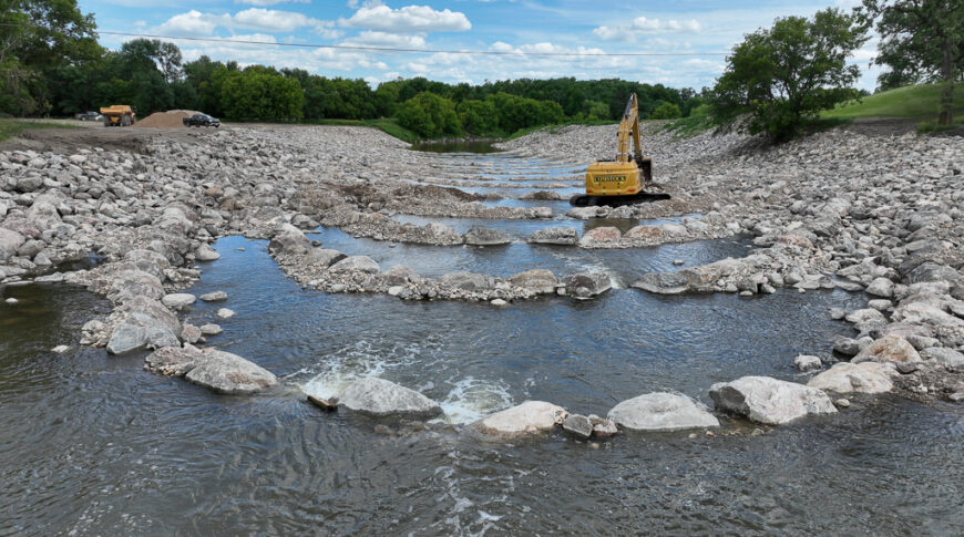 default Goose River rock riffles being placed by big yellow excavator.