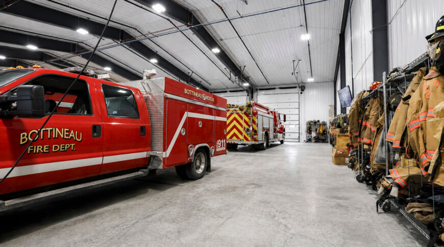 Bottineau Fire Hall - Low Res (11) Interior of Bottineau Fire Hall with prefabricated metal building, concrete floors, fire trucks and shelves of firefighters clothing.