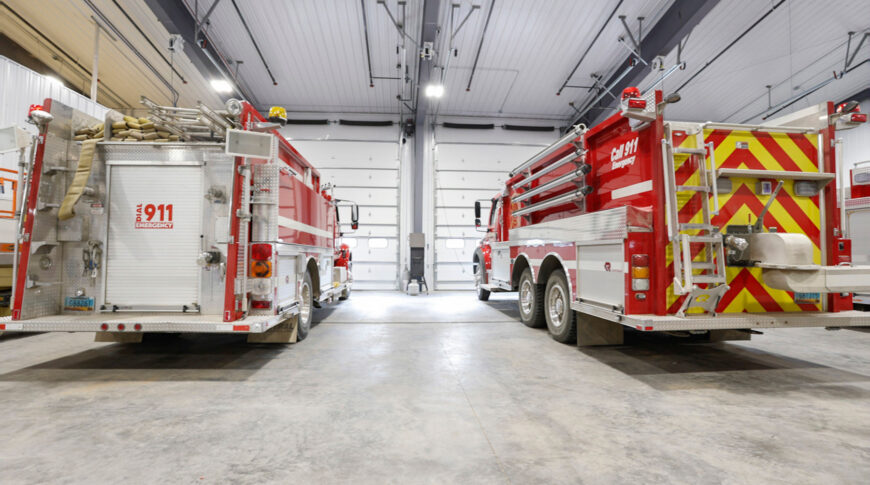 Bottineau Fire Hall - Low Res (13) Interior of metal prefabricated fire hall facing garage doors and backs of two fire trucks.