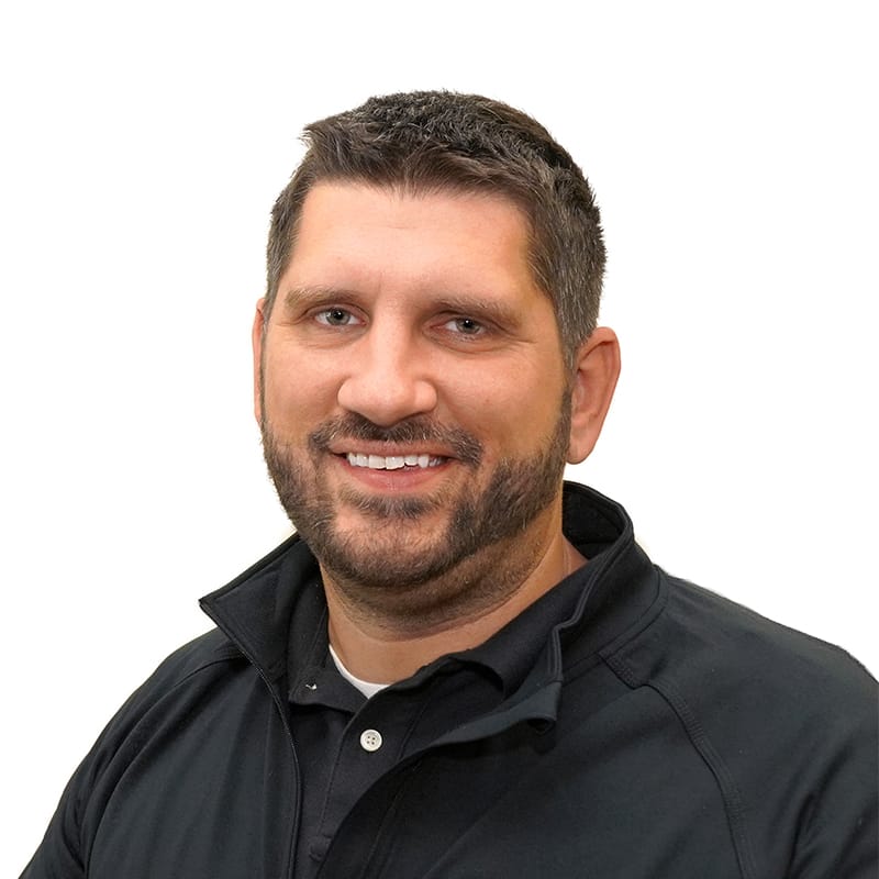 Middle-aged man with tan skin, short brown hair, brown scruffy beard, and black polo.