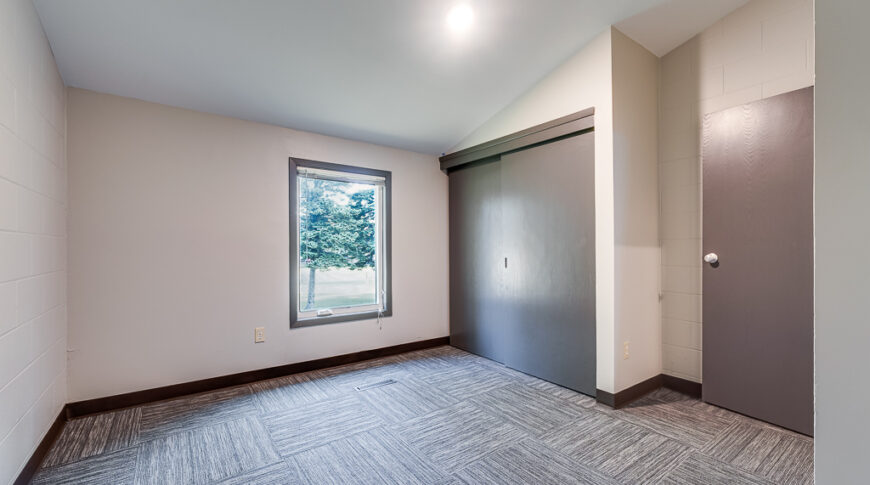 Newly remodeled bedroom with updated carpet flooring and white wall paint.