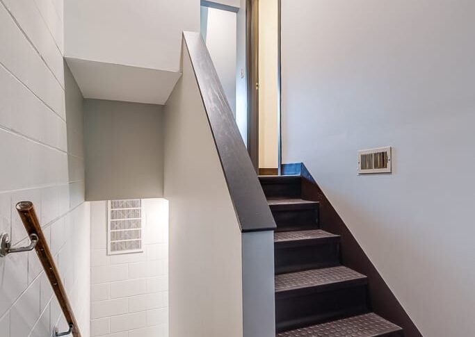 Newly treaded stairwell with updated light fixtures and white paint on the walls.