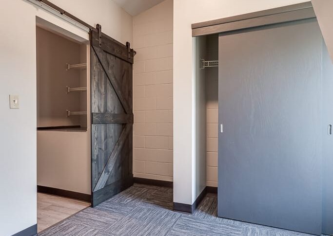 New sliding barn door, new carpet, and fresh white paint in the third-floor bedroom at NDSCS College Townhomes
