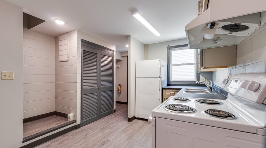 Interior of townhome kitchens post-renovation with updated kitchen cabinetry and countertops and new landing on stairs with updated paint and lvp flooring throughout.