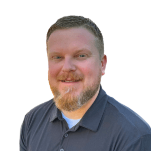 Middle aged man with ruddy complextion and blue eyes with light redish-tinted beard wearing dark blue polo.