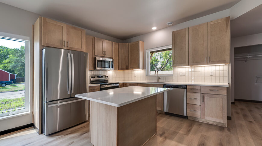 Bison Run Rentals - Low Res-16 Modern scandinavian-designed kitchen with light wood cabinetry and white countertops and tiled backsplash.