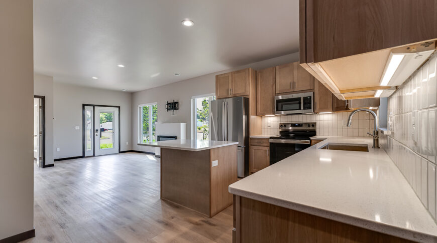 Bison Run Rentals - Low Res-17 Modern scandinavian style kitchen with light wood cabinets and island overlooking great room with fireplace.