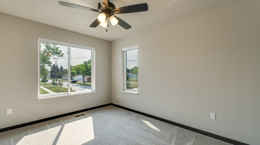 Bison Run Rentals - Low Res-28 Interior bedroom view with greige walls, windows, ceiling fan, and carpet.