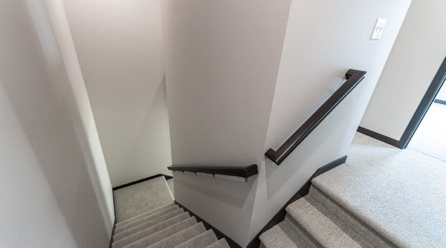 Bison Run Rentals - Low Res-5 Stairwell with greige walls, light gray carpet and dark black coving and railings.