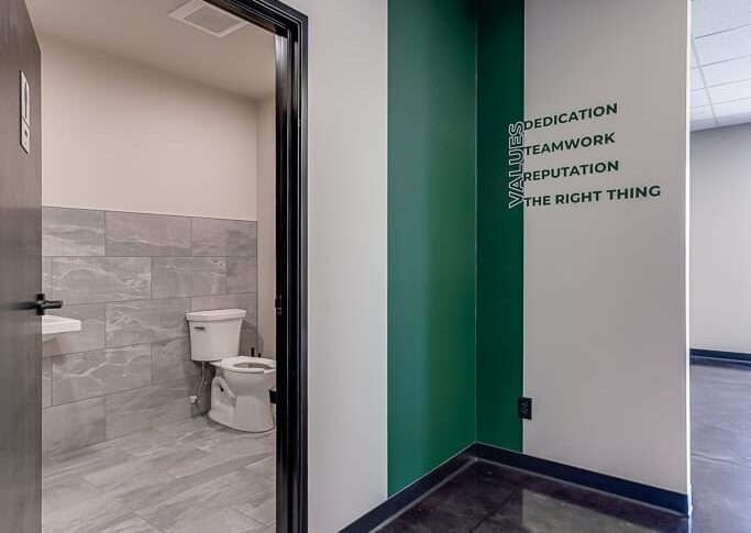 Comstock Construction Aberdeen-Low Res-32 L-shaped nook with green stripe down wall and the words "Values: Dedication, Teamwork, Reputation, The Right Thing."