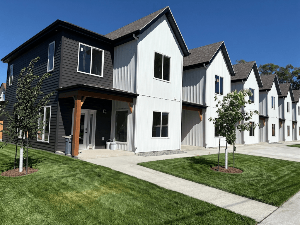 FIREFL~1 Exterior of Bison Lodge townhomes 6-plex with blue skies and green grass.