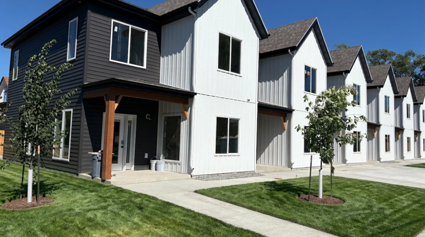 FIREFL~1 Exterior of Bison Lodge townhomes 6-plex with blue skies and green grass.