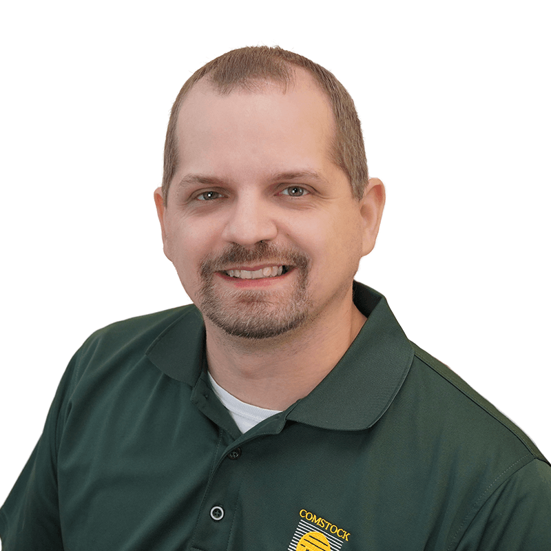 JShannon_800x800 Middle-aged man white short receding dark blonde hair and green eyes and goatee wearing dark green polo shirt.